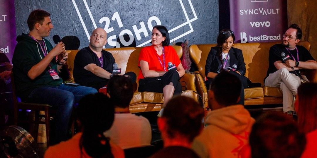 A panel discussion on stage at 21Soho, with an audience watching