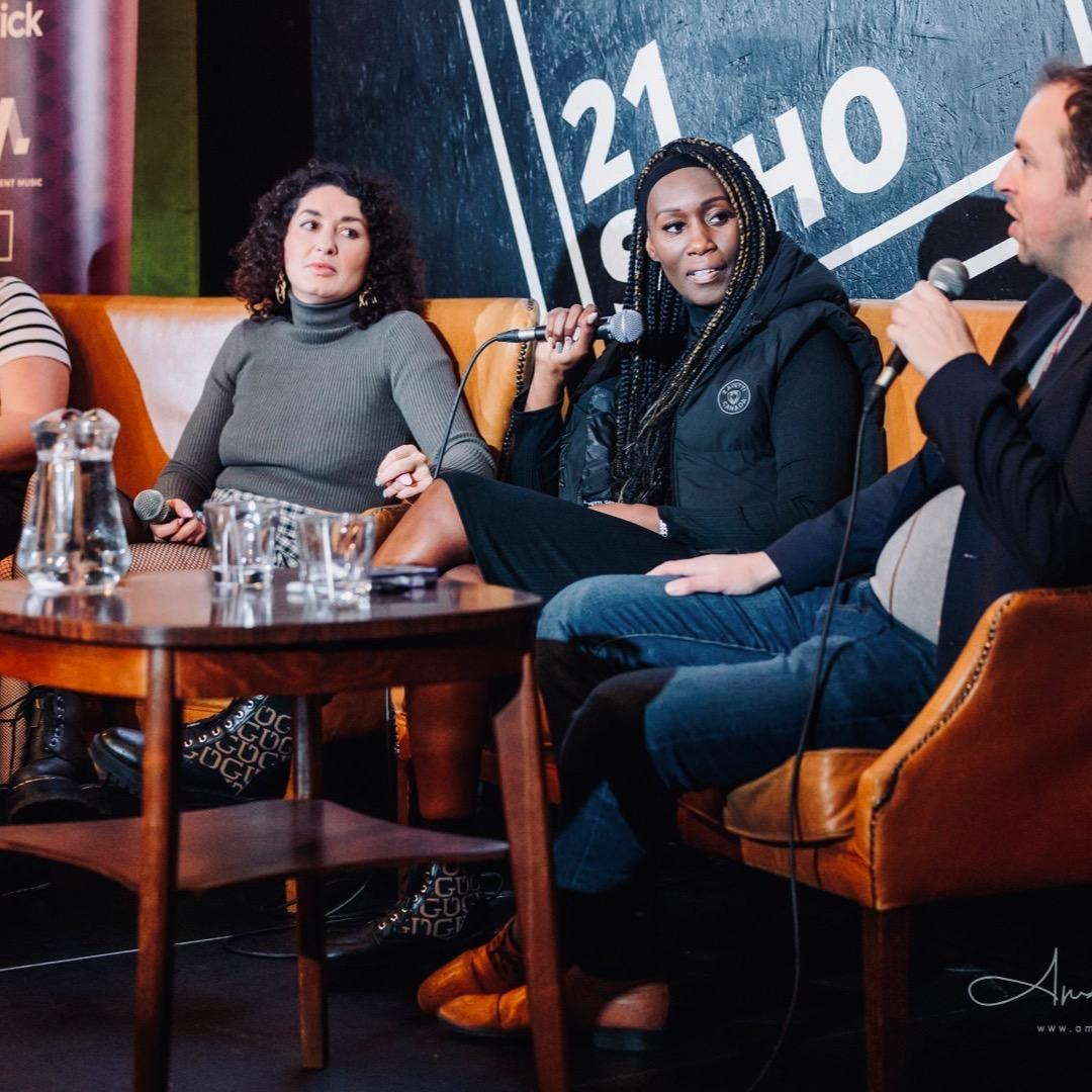A four-person panel sitting on sofas at the FFWD conference, the 21Soho sign on the wall behind them